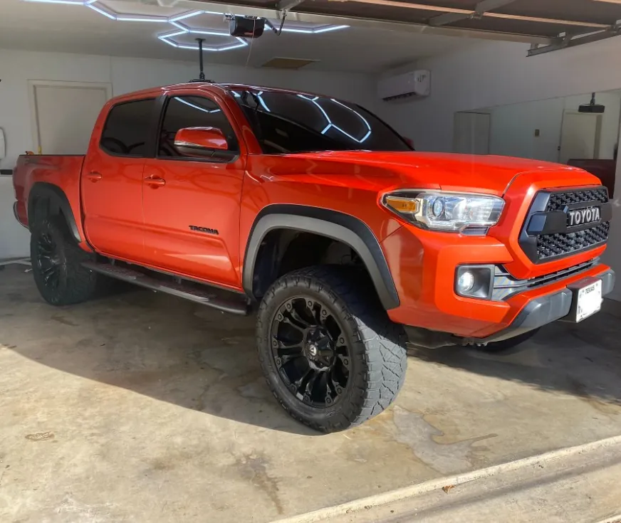 Orange Toyota Tacoma with tinted windows in a San Antonio shop
